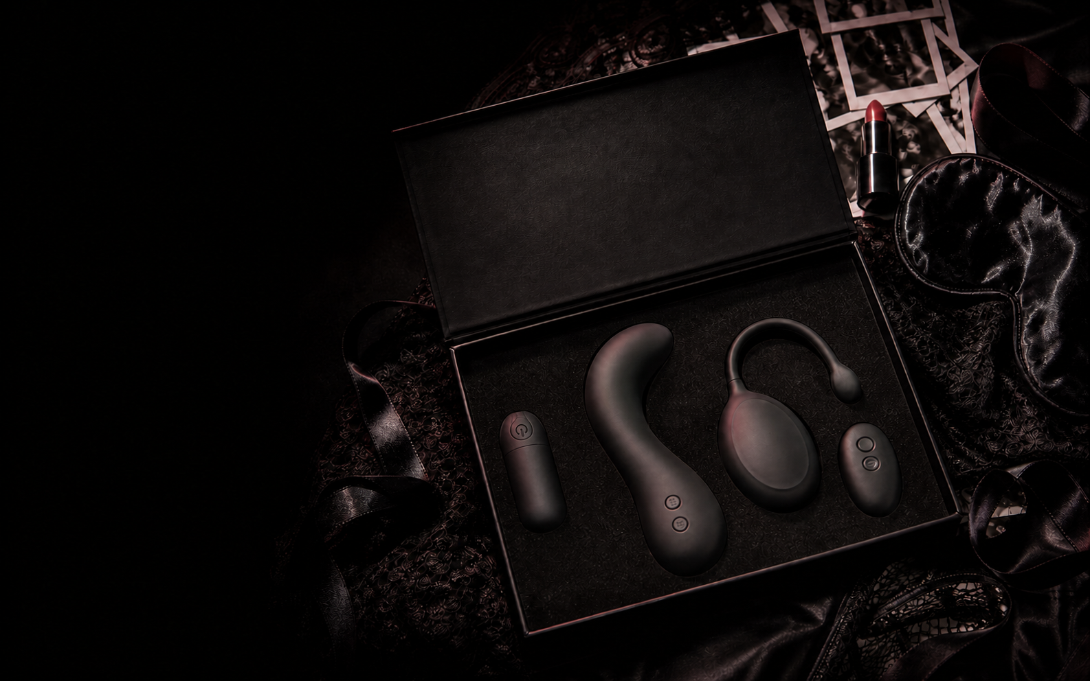 Open black After Hours gift box containing the Whisper Mini vibrator, Tremble curved massager, and Velvet Sync wearable with its remote