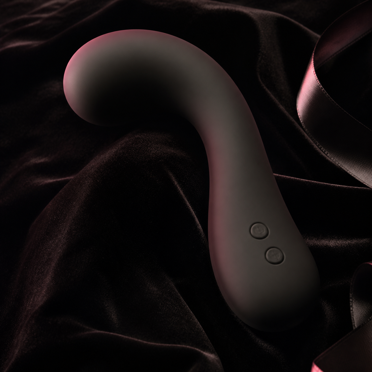 Curved matte-black massager on black velvet and satin